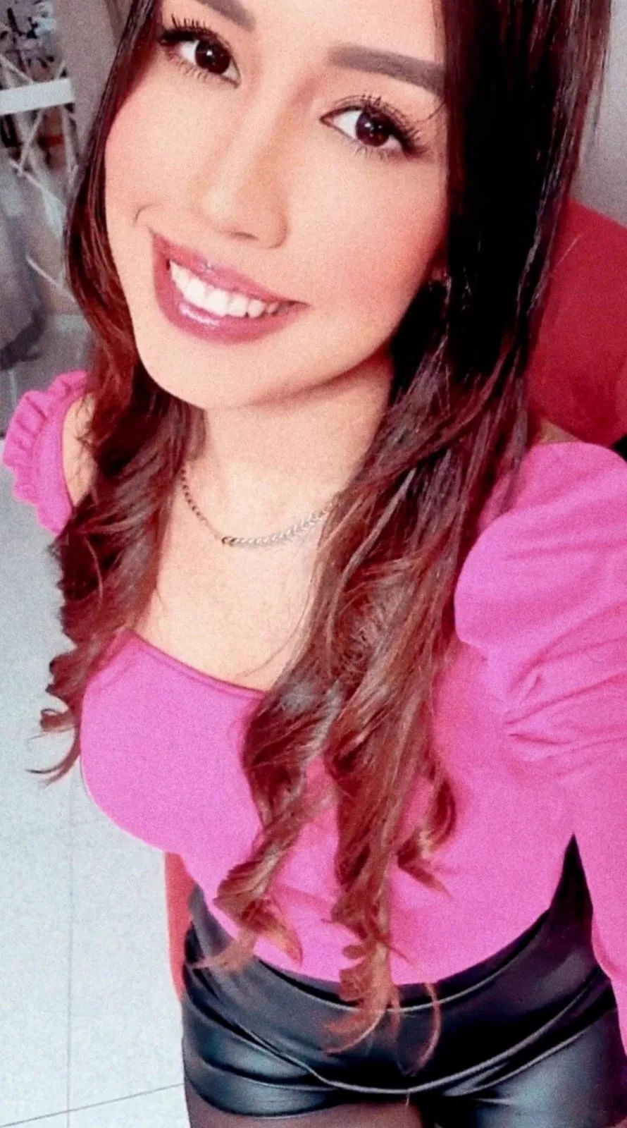 Bruna sorrindo com blusa rosa.